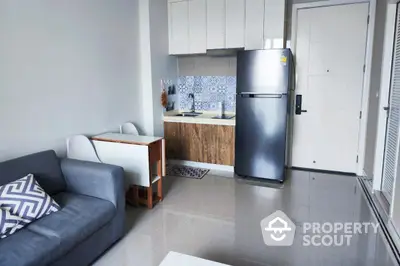 Modern compact kitchen with sleek appliances and cozy living area in stylish apartment.