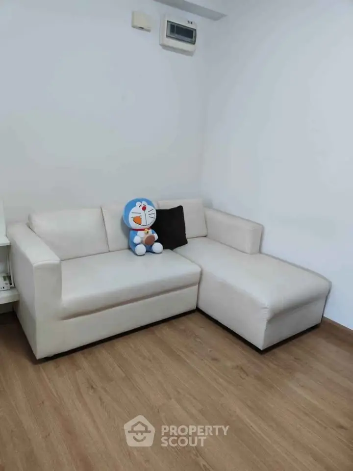 Modern living room with white sectional sofa and wooden flooring, perfect for cozy relaxation.