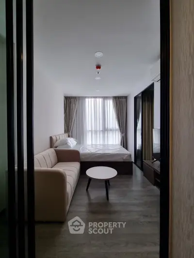 Modern bedroom with cozy sofa and natural light, perfect for relaxation and comfort.
