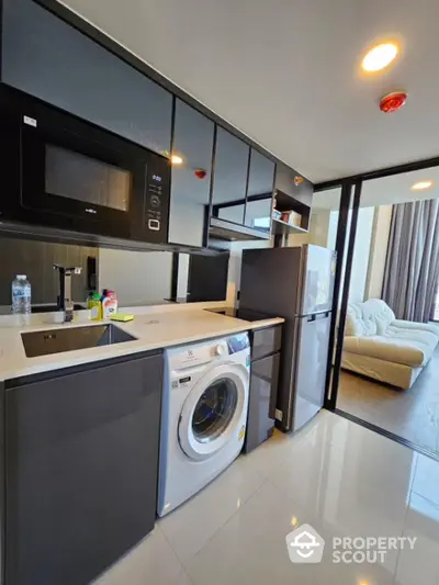 Modern kitchen with sleek appliances and open layout leading to cozy living room