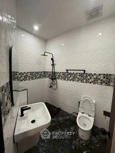 Modern bathroom with stylish black and white tile design and sleek fixtures.