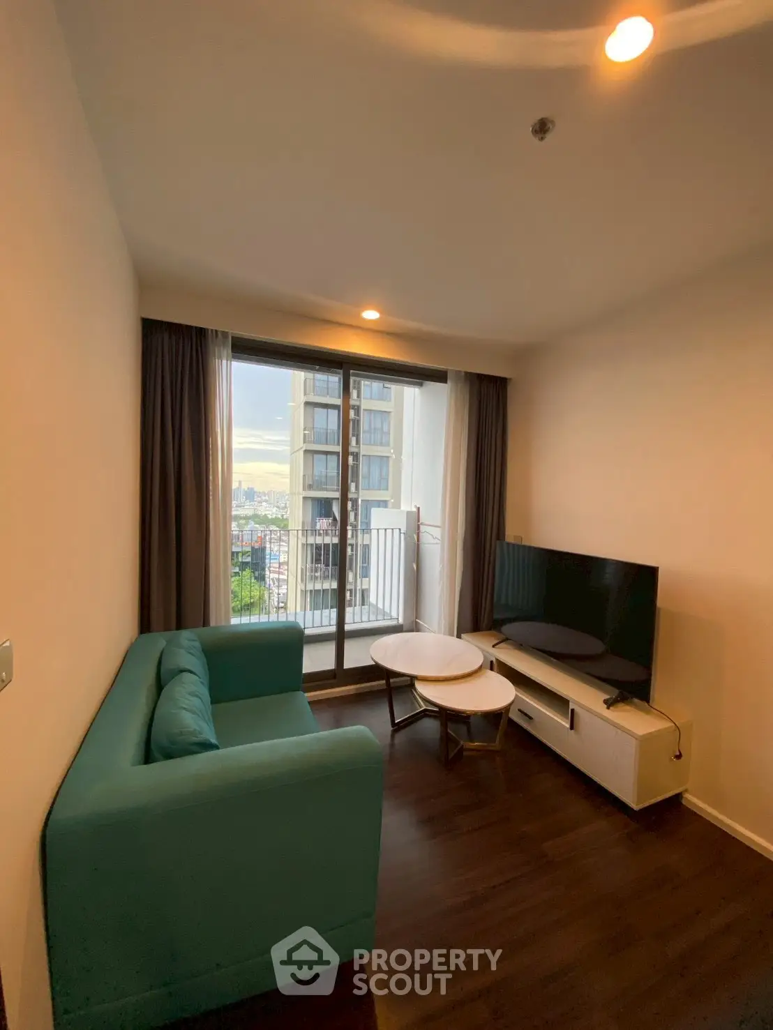 Cozy living room with modern furniture and balcony view in a high-rise apartment.