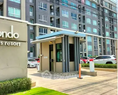 Modern condominium entrance with security booth and parking area