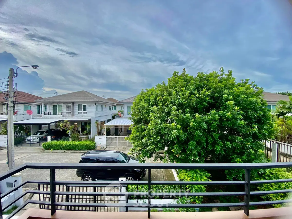 Charming suburban neighborhood view from balcony with lush greenery and modern houses.