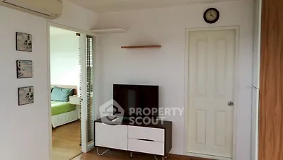 Modern living room with TV and view into cozy bedroom