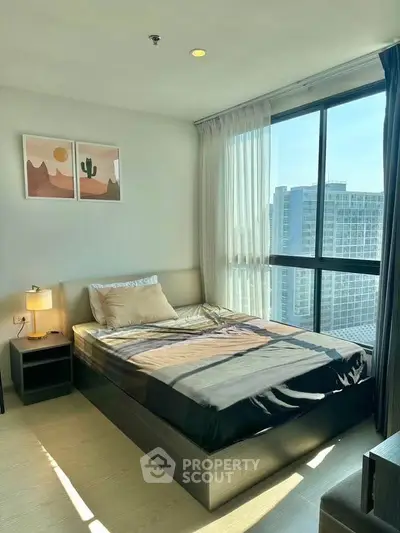 Modern bedroom with large window offering stunning city view in high-rise apartment.