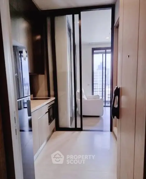 Modern apartment hallway leading to a bright living room with city views.