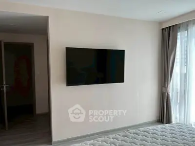 Modern bedroom with wall-mounted TV and large window with curtains