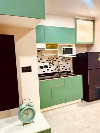 Modern kitchen with green cabinets, microwave, and sleek design