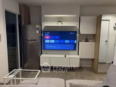 Modern living room with sleek TV setup and stainless steel fridge, perfect for urban living.
