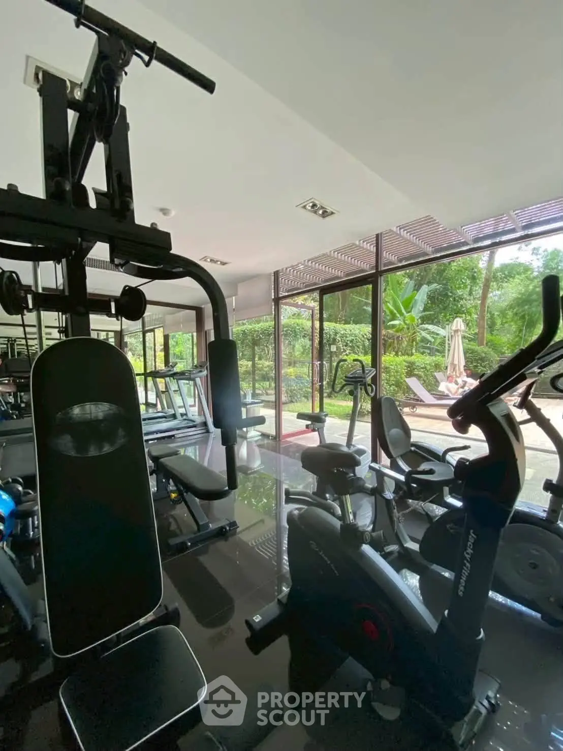 Modern gym with state-of-the-art equipment and lush garden view, perfect for fitness enthusiasts.