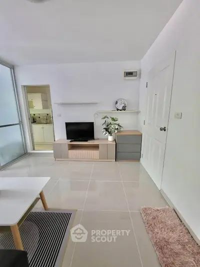 Modern living room with sleek design and natural light, featuring a TV stand and minimalist decor.
