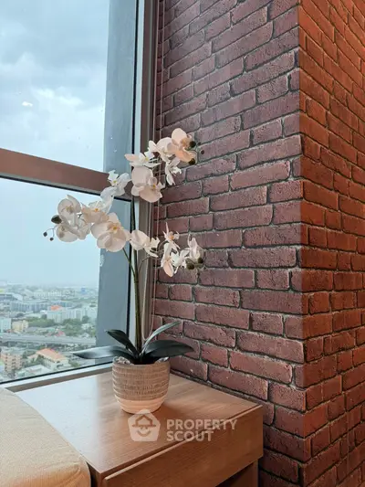 Stylish interior corner with brick wall and city view, featuring elegant white orchid decor.