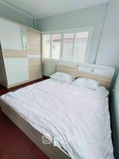 Cozy bedroom with modern wooden furniture and large window for natural light.