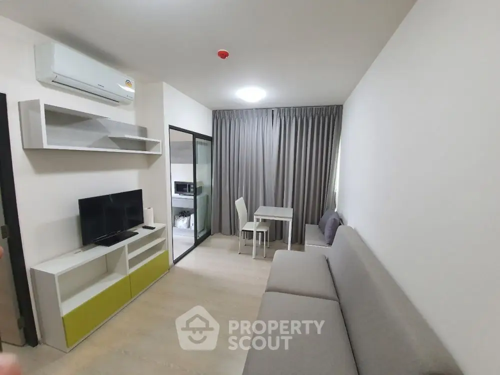 Modern living room with sleek furniture and open layout, featuring a cozy dining area and air conditioning.