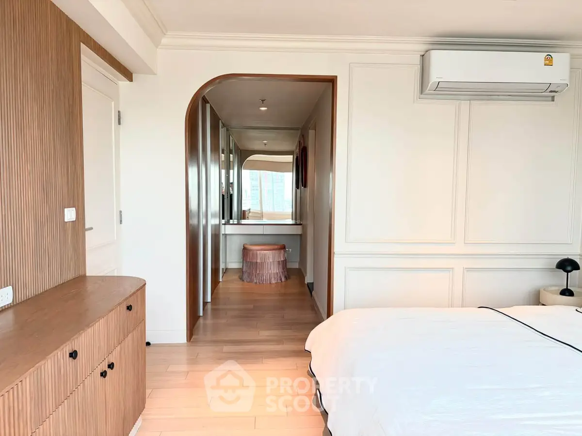 Elegant bedroom with modern decor and air conditioning, featuring a stylish vanity area and wooden flooring.