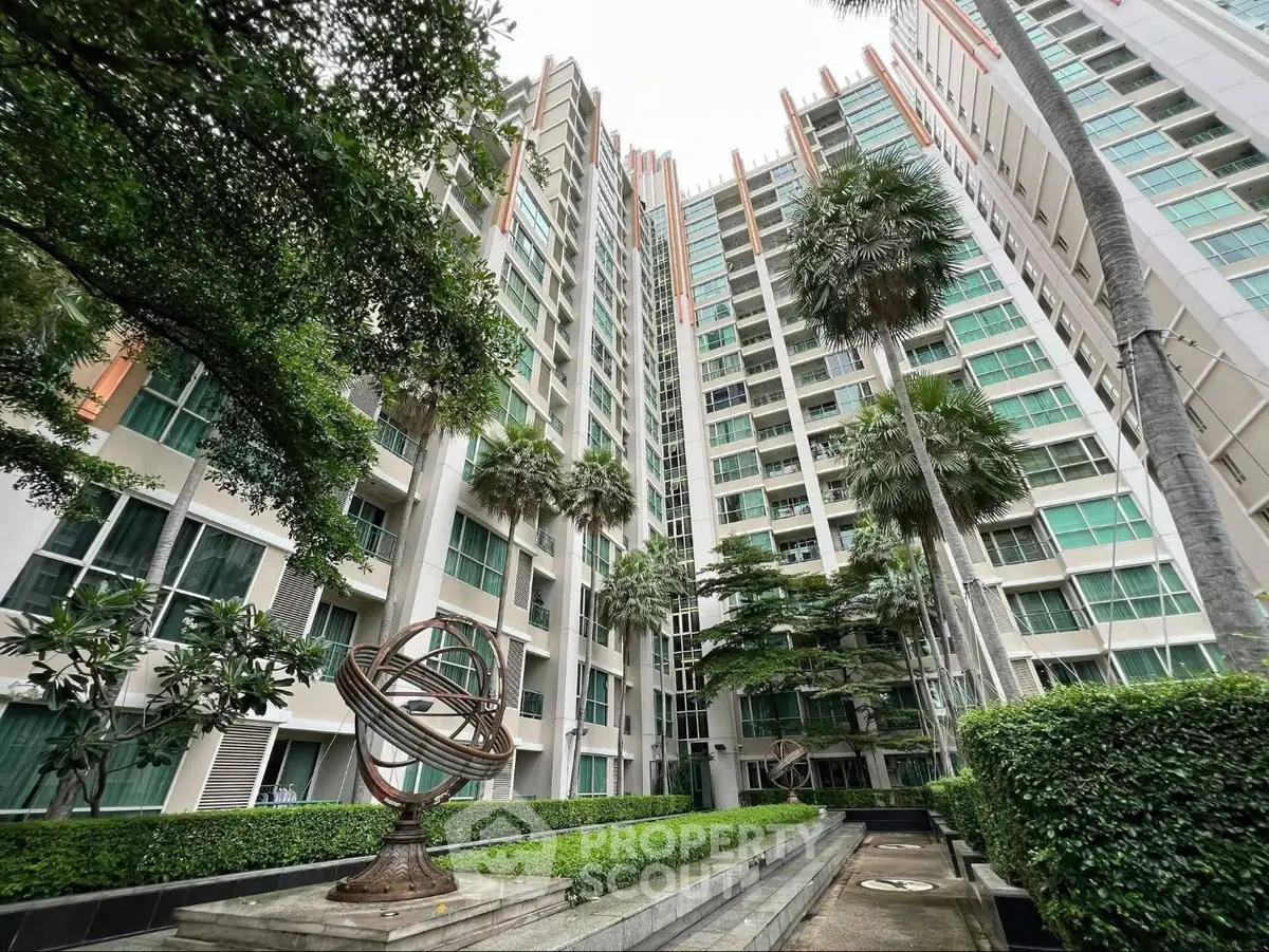 Modern high-rise residential building with lush greenery and unique sculpture in courtyard.