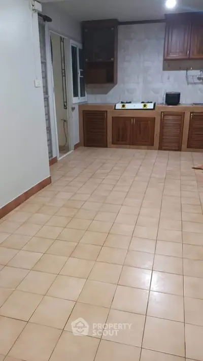 Spacious kitchen with tiled floor and wooden cabinets, ideal for culinary enthusiasts.