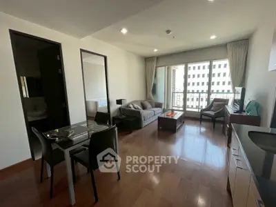 Spacious modern living room with wooden flooring and large windows in a stylish apartment.