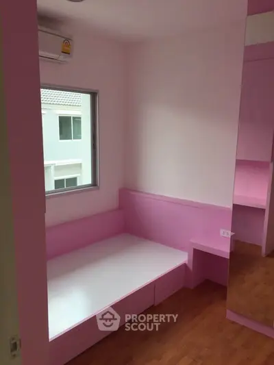 Charming pink-themed bedroom with built-in furniture and natural light.