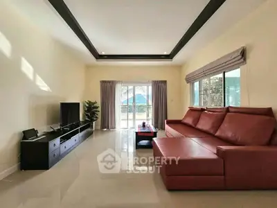 Spacious living room with modern red sofa and large windows offering natural light.