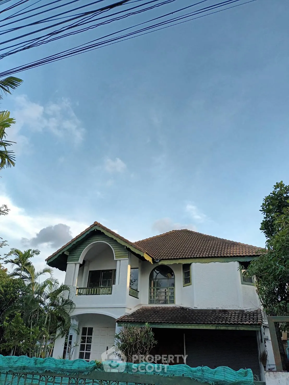 Charming two-story house with lush greenery and a tiled roof, perfect for family living.