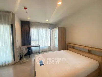 Spacious bedroom with large windows and modern furnishings in a well-lit apartment.