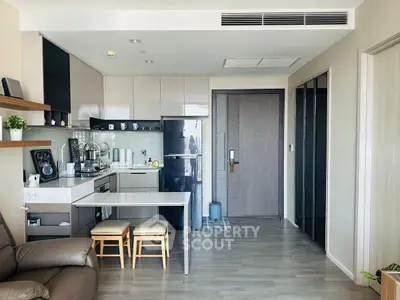 Modern open-layout kitchen with sleek cabinetry and dining area in stylish apartment.