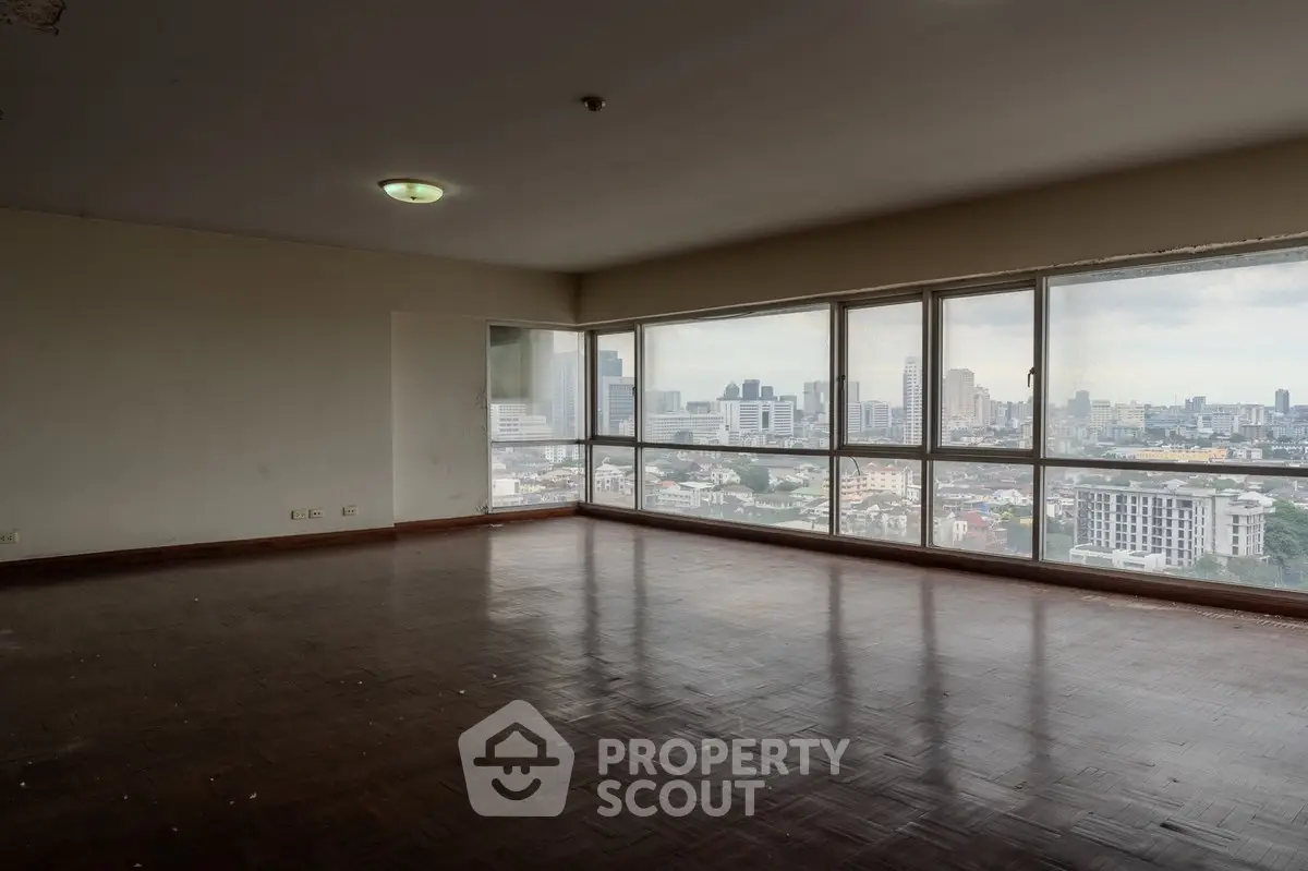 Spacious corner unit with panoramic city views and large windows in a high-rise building.