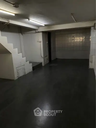 Spacious basement area with tiled flooring and staircase, ideal for storage or renovation.