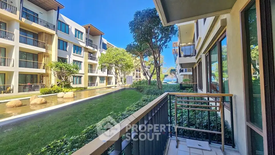 Modern apartment complex with lush garden and serene water feature view.