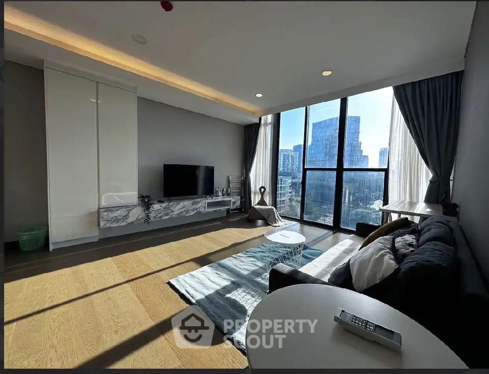 Modern living room with large windows and city view, featuring sleek furniture and stylish decor.