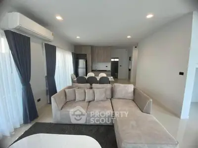 Modern living room with plush sectional sofa and open kitchen layout, featuring sleek appliances and elegant decor.