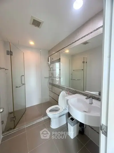 Modern bathroom with glass shower and sleek fixtures in contemporary apartment.