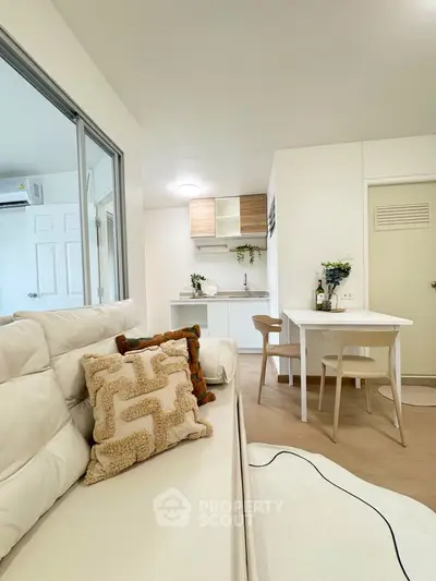 Modern open-plan living room with cozy seating and stylish dining area in a bright apartment.