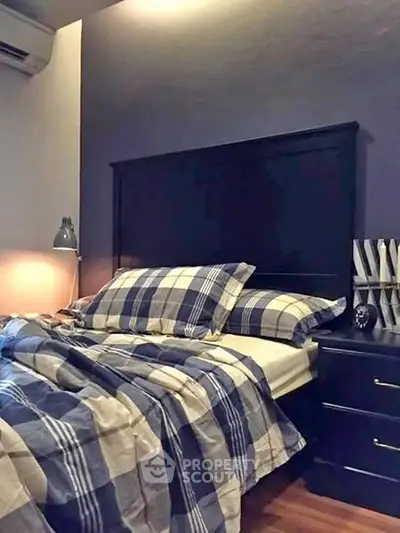 Cozy bedroom with stylish plaid bedding and modern bedside lamp