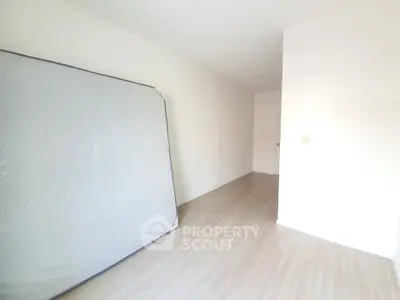 Spacious empty room with wooden flooring and a mattress, ideal for customization.