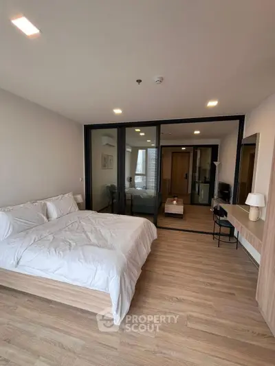 Modern bedroom with wooden flooring and large glass partition in a stylish apartment.