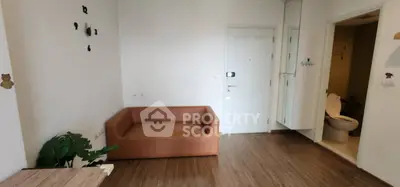 Cozy living area with modern sofa and wooden flooring adjacent to a bathroom.