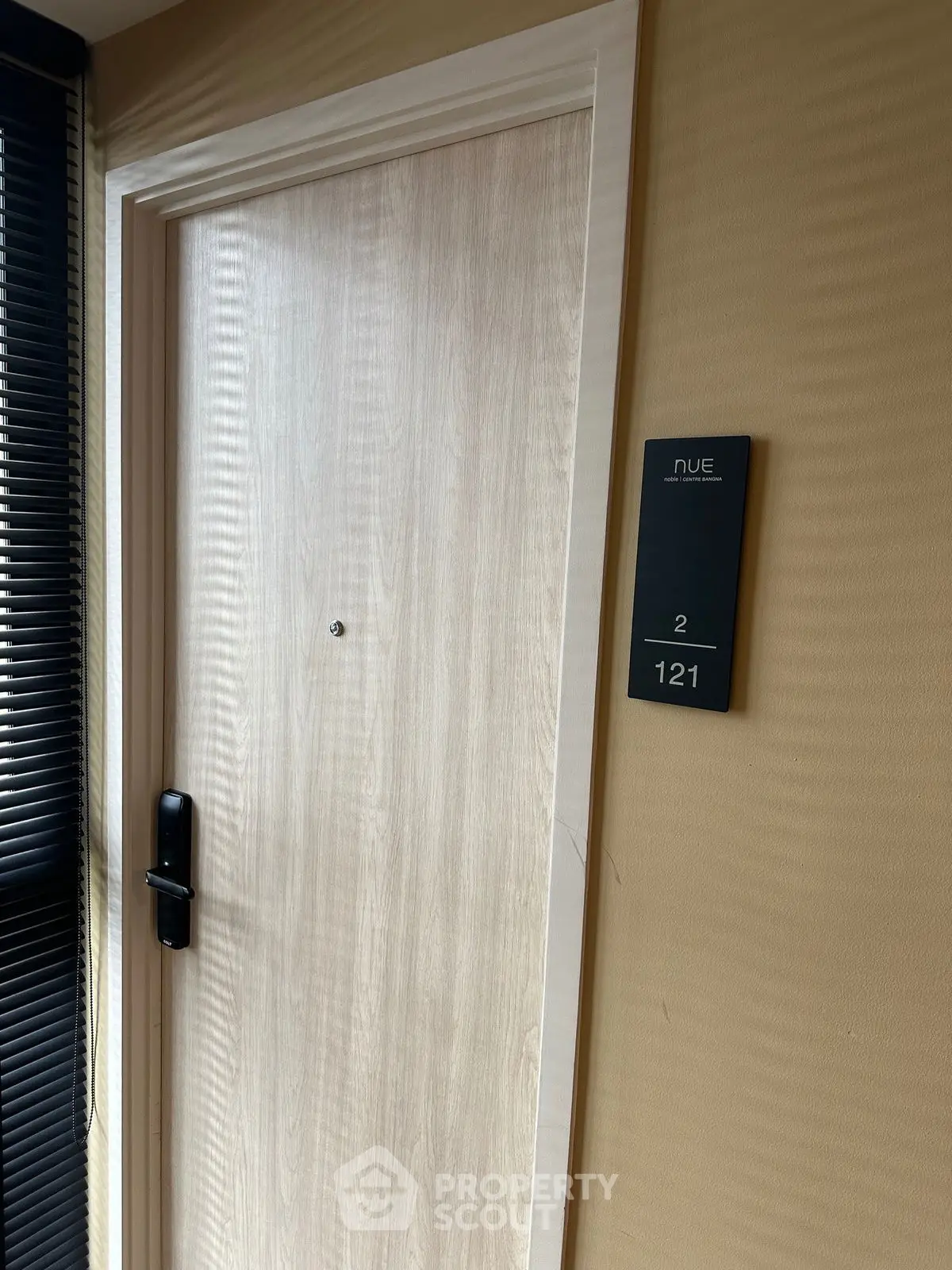 Modern apartment entrance with sleek wooden door and stylish room number plaque.
