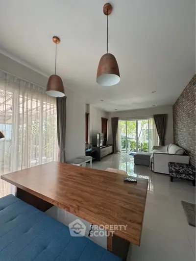 Spacious living room with modern decor and large windows opening to a lush garden view.