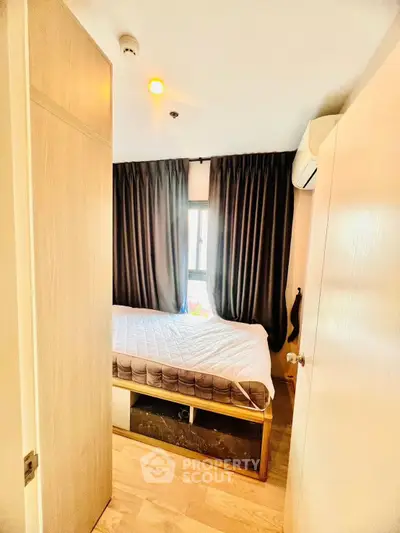 Cozy bedroom with modern design, featuring a comfortable bed and natural light through large windows.