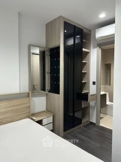Modern bedroom with sleek storage and ensuite bathroom in contemporary apartment.