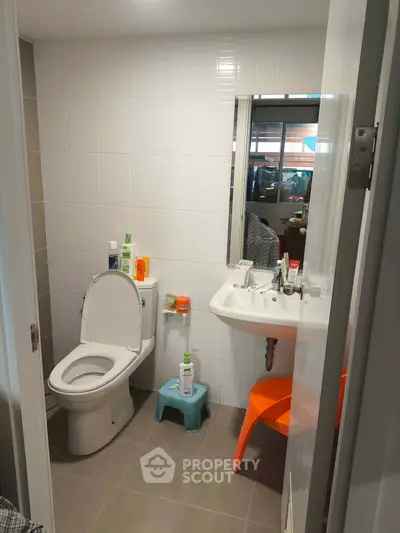 Modern bathroom with white tiles and contemporary fixtures in a cozy apartment.