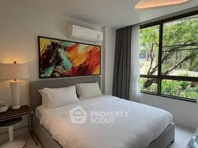 Modern bedroom with large window and vibrant artwork, offering a serene garden view.