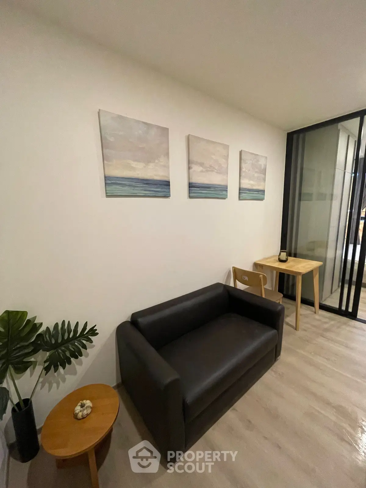 Modern living room with sleek black sofa, minimalist decor, and stylish wall art in a cozy apartment.