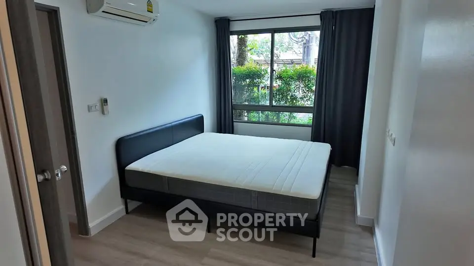Spacious bedroom with large window and modern furnishings in a serene setting.