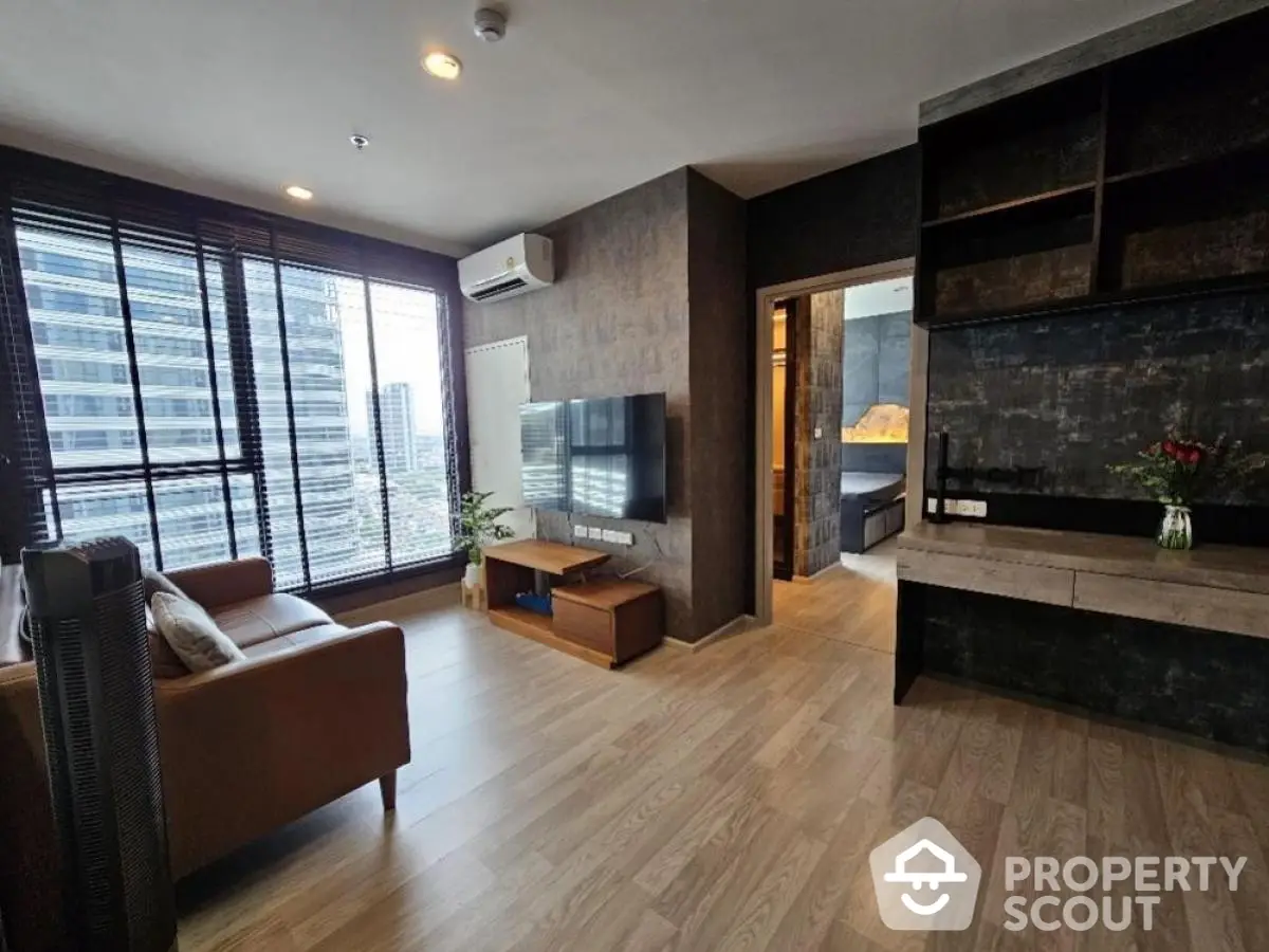 Modern living room with large windows and city view, featuring stylish decor and wooden flooring.