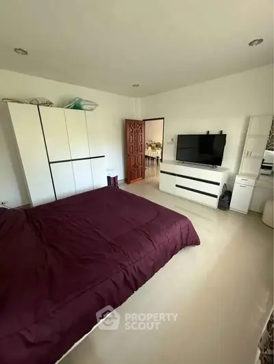 Spacious bedroom with modern furniture and TV, featuring a cozy atmosphere and ample storage space.