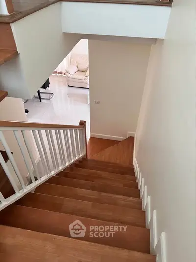 Spacious interior with wooden staircase leading to a bright living area, showcasing modern design and comfort.